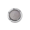 Silver compact folding table bag hook or portable purse hanger with a round, textured surface.