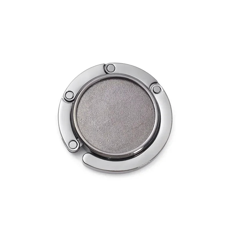 Silver compact folding table bag hook or portable purse hanger with a round, textured surface.
