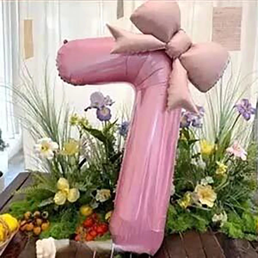 Pink 32-inch number balloons with matte bow decor set of two displayed among greenery and flowers