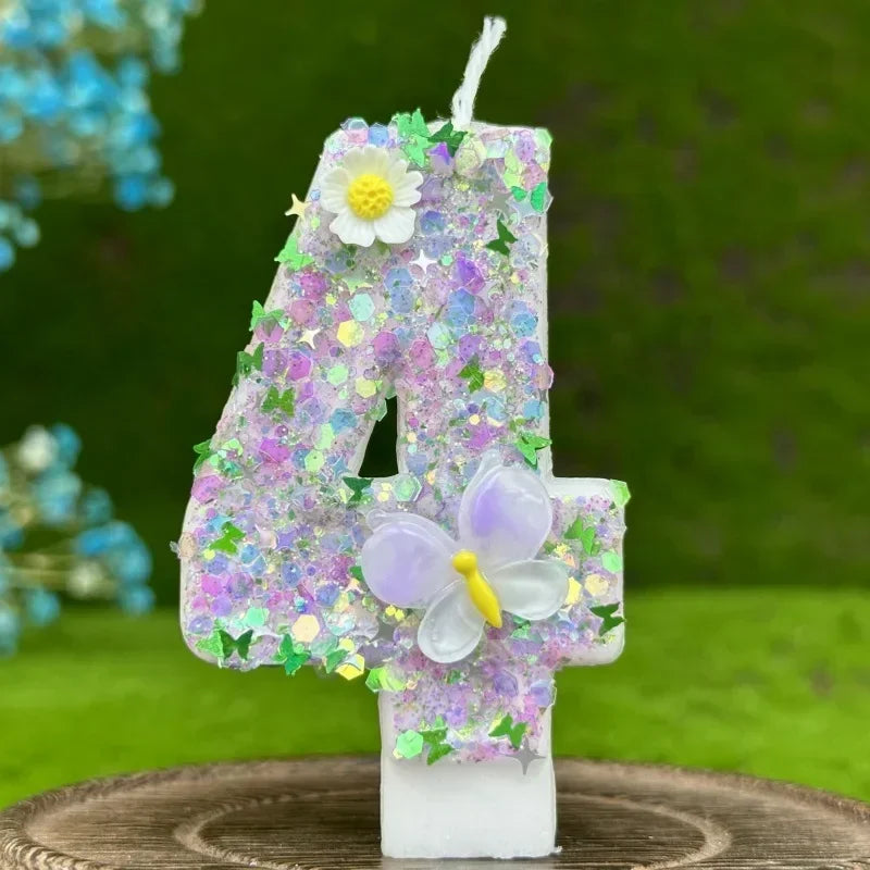 A large purple glitter number four candle decorated with a white flower and a translucent purple butterfly