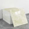A stack of rectangular faux marble wall tiles in pale cream and beige tones displayed on a gray surface.