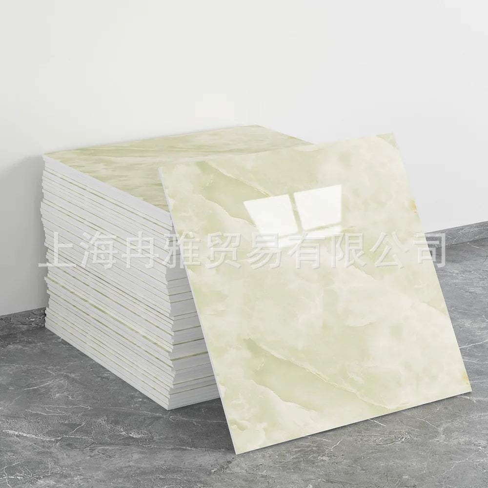 A stack of rectangular faux marble wall tiles in pale cream and beige tones displayed on a gray surface.