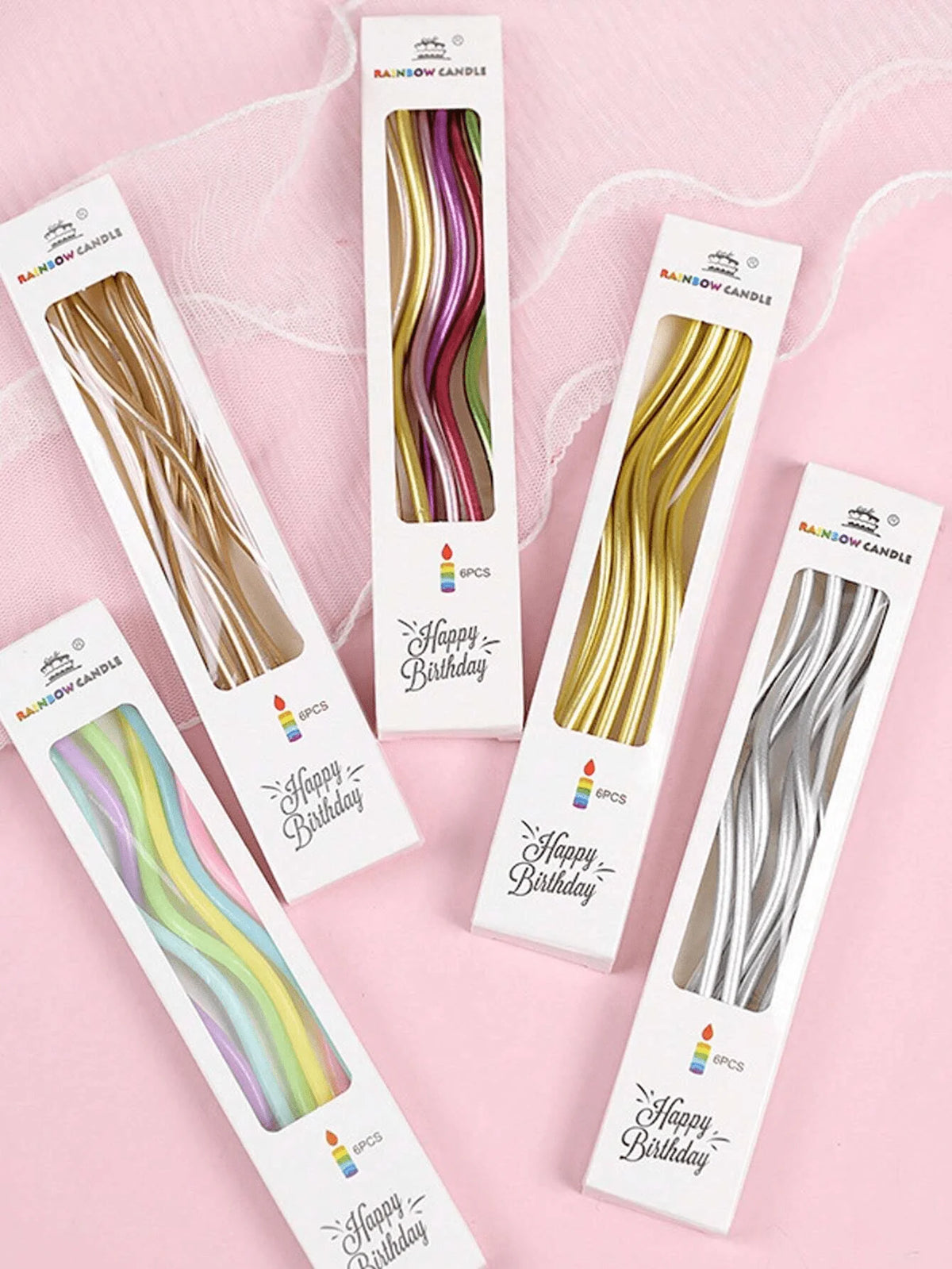 A collection of rainbow spiral birthday candles in individual packaging with star toppers.