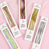 A collection of rainbow spiral birthday candles in individual packaging with star toppers.
