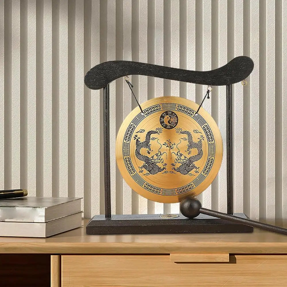 A brass Feng Shui Zen table gong featuring dragon and Taiji symbols mounted on a dark stand.