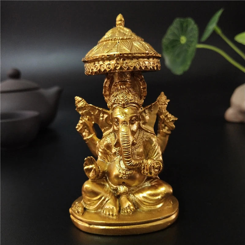 A golden bronze statue of Ganesha Buddha seated in a meditative pose on a round base.