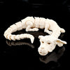 Figurine de dragon peinte à la main, sculptée en matériau blanc, posée sur une surface noire réfléchissante.