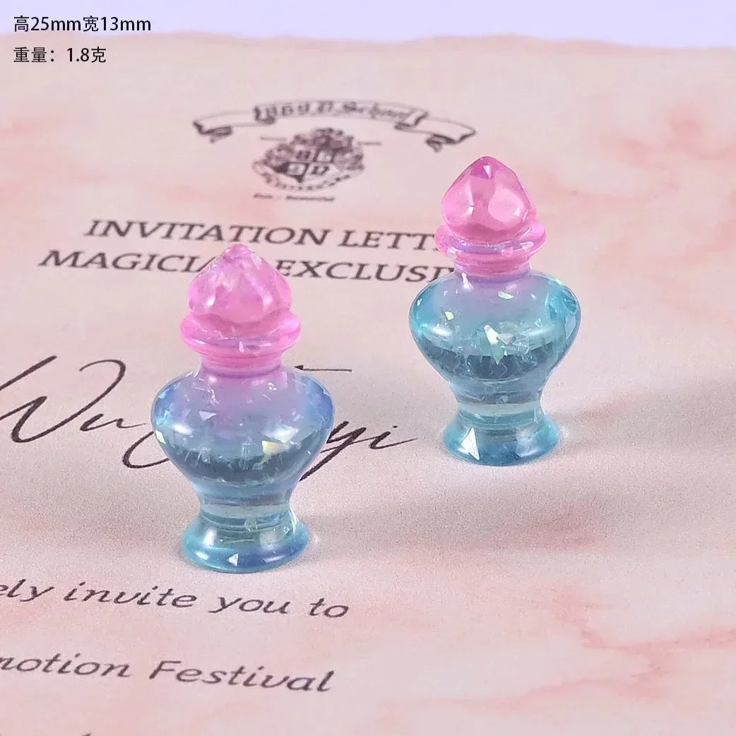 Two small, translucent blue resin potion bottles with pink caps displayed on a pink background.
