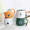 A set of three ceramic mugs in orange, white, and green featuring cartoon graffiti stickers.