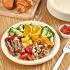 A plate of fresh salad with sliced meat, vegetables, and tomatoes served on a wooden table.
