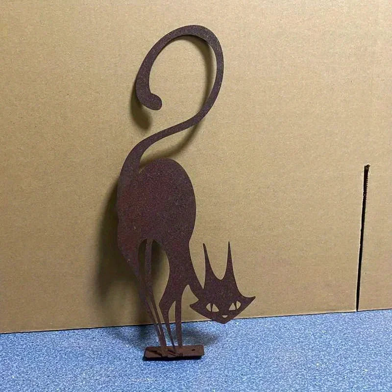 A dark brown wrought iron cat ornament with a curved tail and pointed ears mounted on a blue surface.