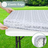 A hand is placing an elastic edge tablecloth onto a white table, showing the fitted rectangle fabric and the elastic edge det