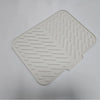 A white silicone drain mat with raised, parallel lines for grip is shown from above.