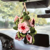 Hand-knitted hanging plant basket with pink and green flowers used as car mirror décor