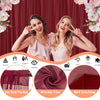 A woman in a pink dress poses in front of a red curtain backdrop with various decorative elements and fabric samples.