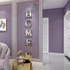 A wall decorated with metallic letters spelling HOME in gold on a purple wall with a butterfly decal above it.