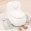 A white plush toy shaped like a toilet paper poop plunger with a smiling face, resting on a sheet of paper.