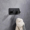 A black self-adhesive wall hook is mounted on a gray wall, with a fluffy white stuffed animal hanging from it.