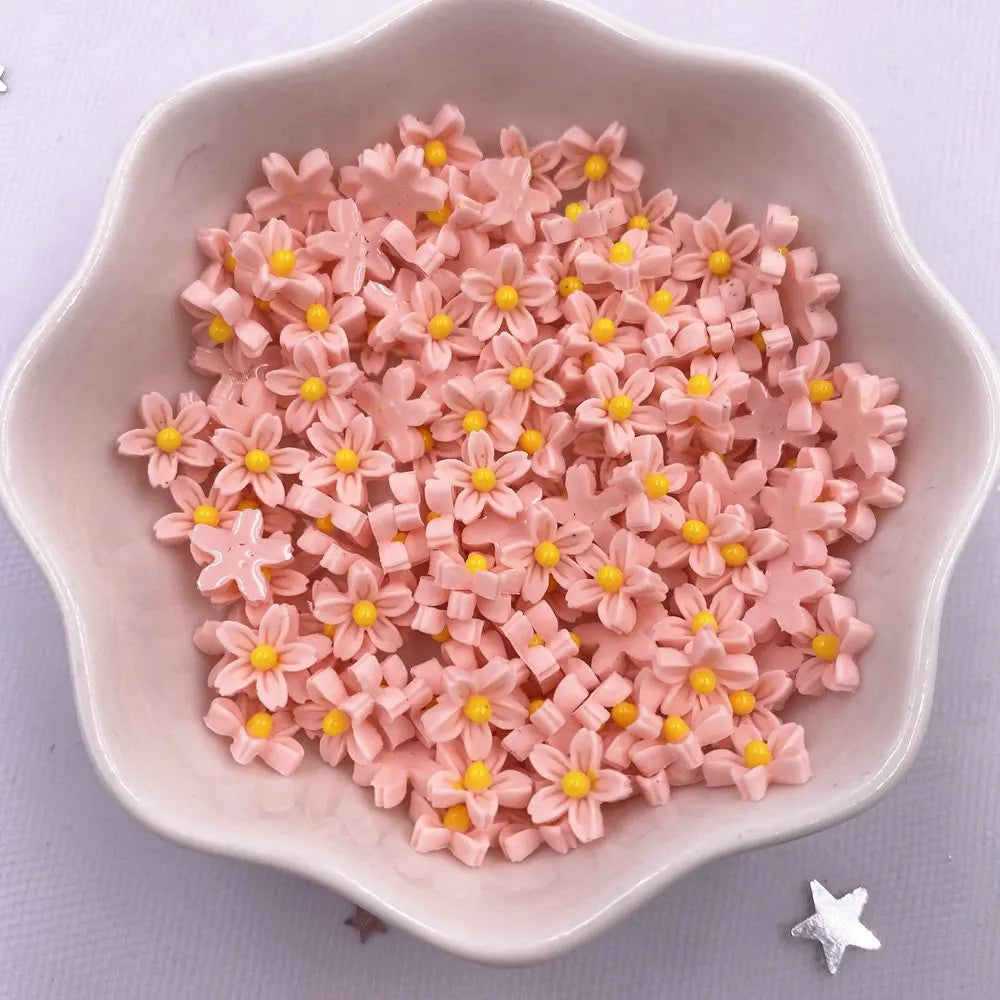 A pile of pink 3D resin flower gems in various shades are displayed in a white dish.