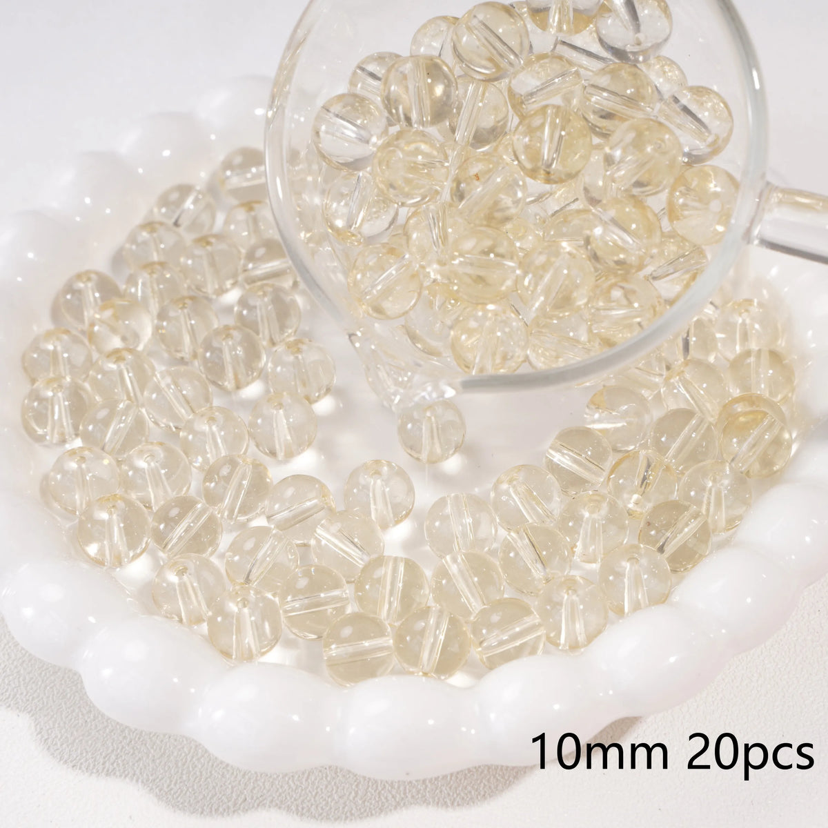 A clear glass spacer bead is shown in a small glass bowl with many beads scattered around it.