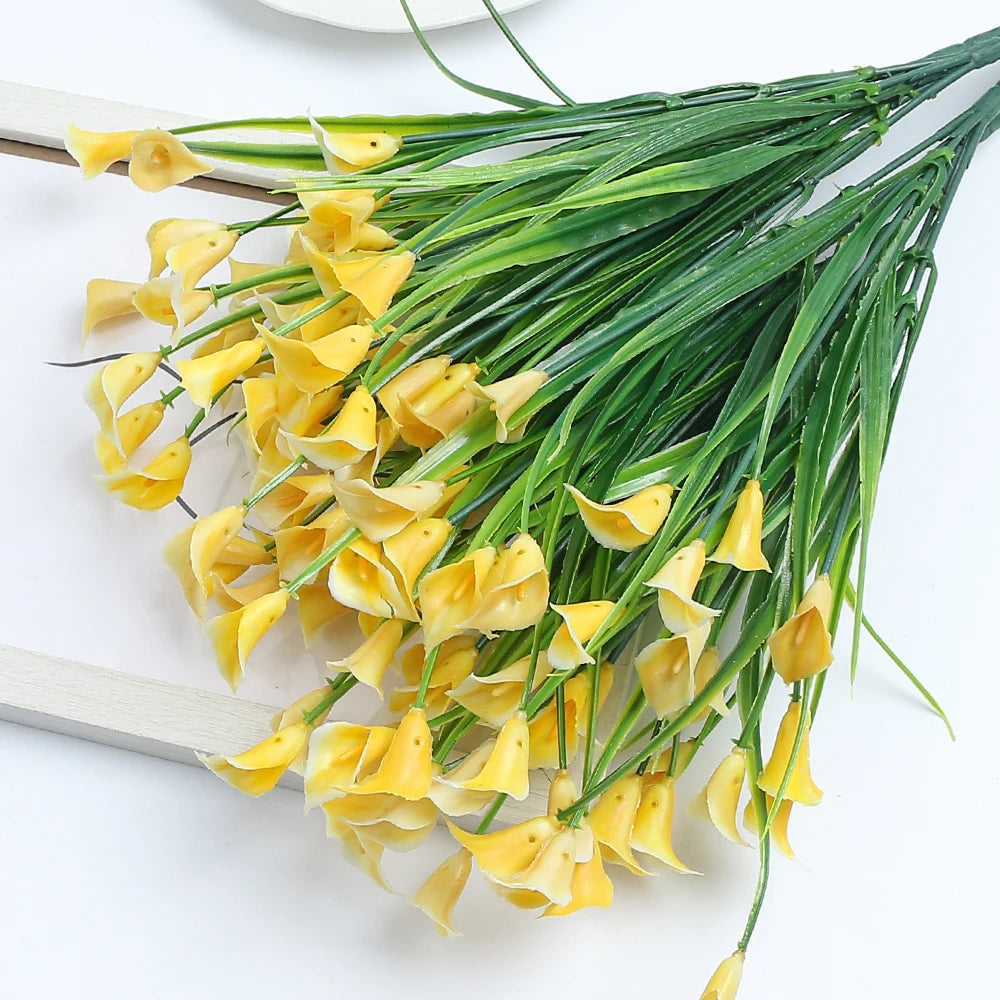 A bouquet of artificial yellow calla lily flowers on a green silk stem.