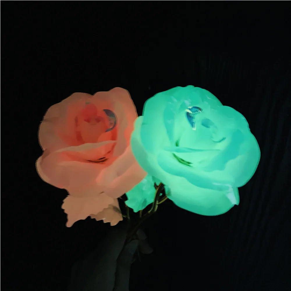 Two glowing roses, one pink and one blue-green, are held against a dark background.