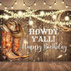 A rustic wooden backdrop featuring cowboy boots and a hat with warm string lights for a birthday party.