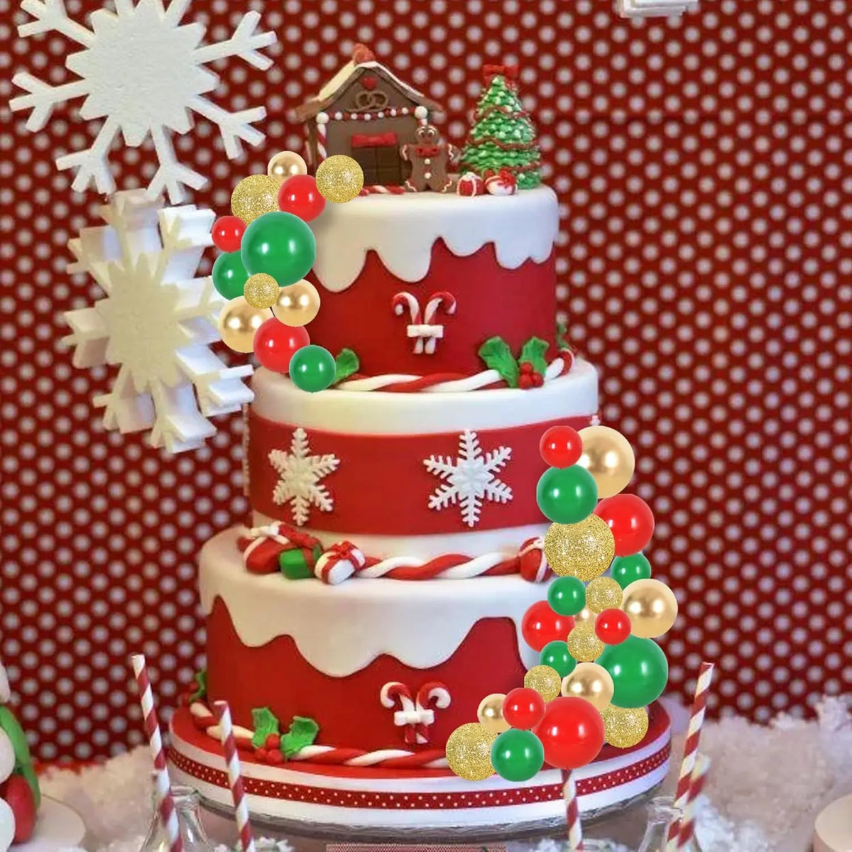 A multi-tiered red and white cake decorated with festive foam ball toppers, including a Christmas tree and a zodiac symbol.
