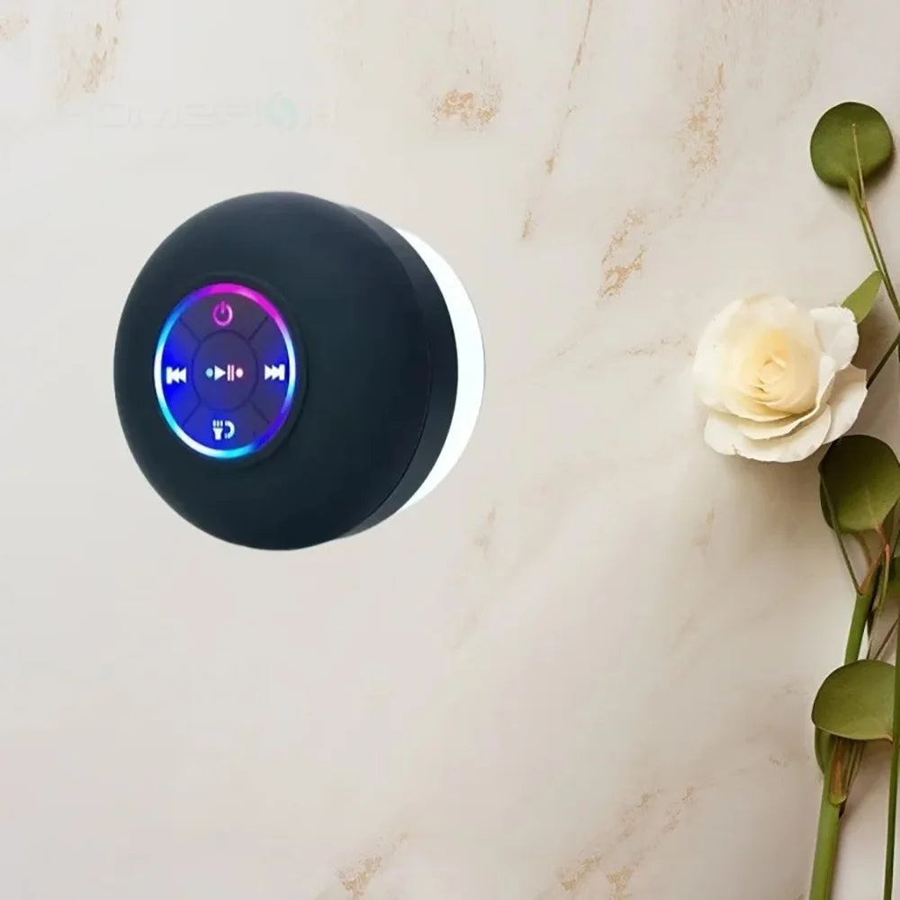 A black waterproof Bluetooth speaker with a white ring and illuminated controls is shown against a light background.