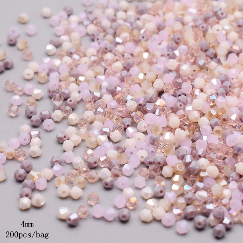 A pile of faceted bicone glass beads in mixed shades of pink, lavender, and cream.