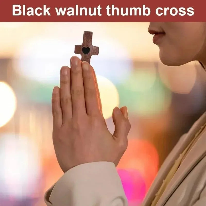 A hand holds a small wooden cross with a heart carved into it for prayer and reflection.