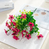 A bouquet of pink and red artificial flowers featuring silk eucalyptus and violet blooms.