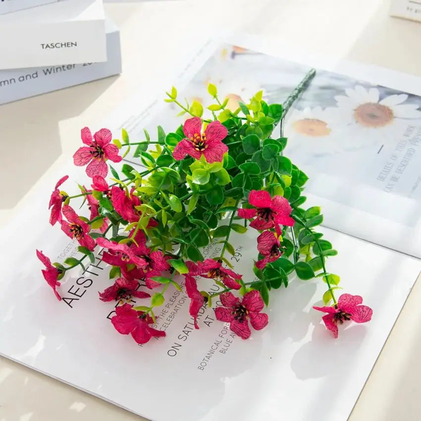 A bouquet of pink and red artificial flowers featuring silk eucalyptus and violet blooms.