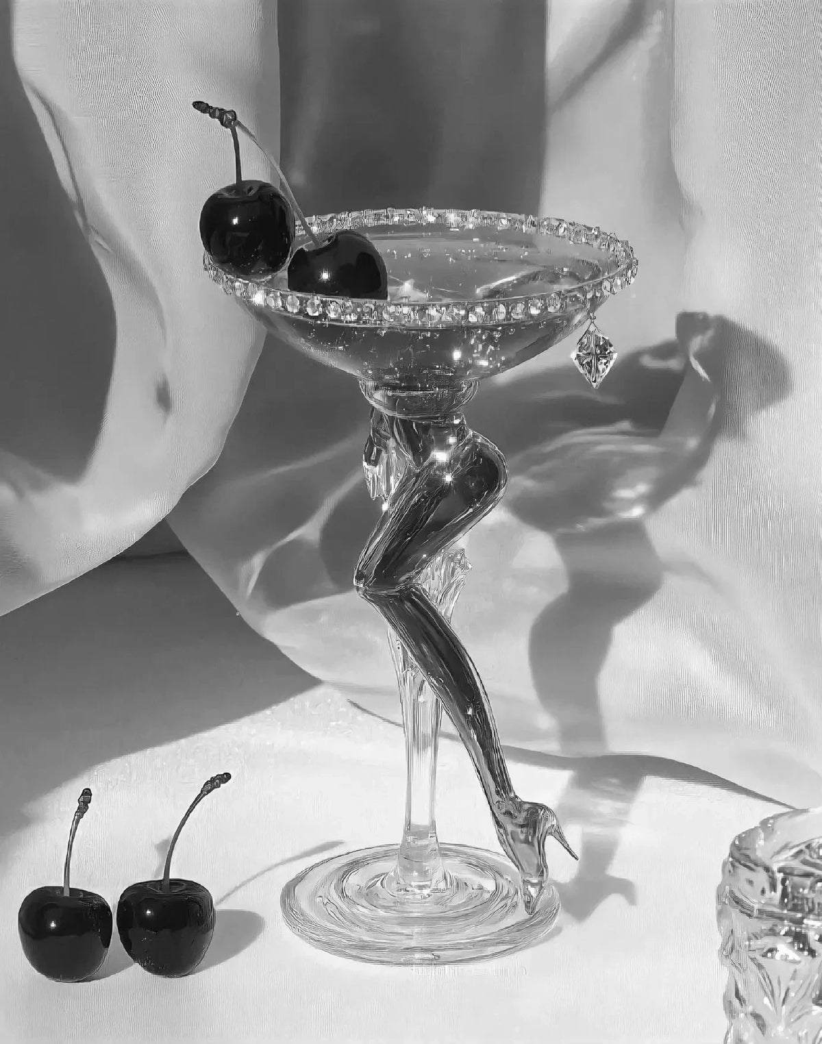 A glass sculpture of a shoe with cherries on the top, set against a white background.