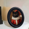 A black wooden photo frame featuring a portrait of a cat wearing a red and white festive collar.