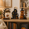 A wooden Halloween decor set featuring ghost, black cat, and pumpkin figurines displayed on a shelf.