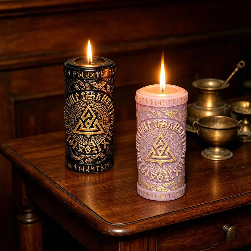 Two lit candles in ornate holders with gold accents resting on a dark wooden surface.