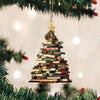Un sapin de Noël décoré de livres empilés suspendus à un ornement doré sur une branche de pin verte.