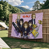 A large flag tapestry featuring characters from the K-On! anime band performing on a stage.