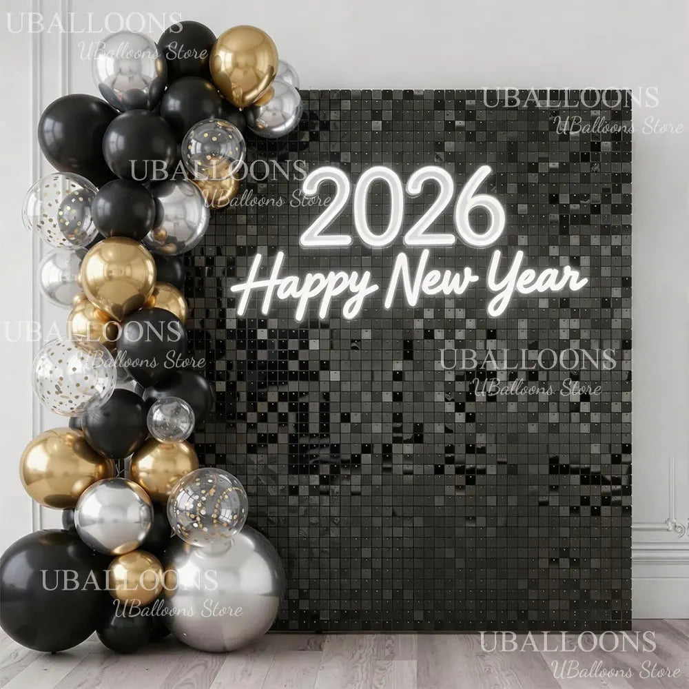 A dark square wall backdrop decorated with gold and silver balloons spelling out Happy New Year for a party.