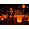 A couple stands silhouetted against a background of numerous glowing, warm-toned lanterns at night.