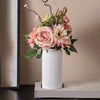 Ein Strauß rosa und pêche Blüten in einer weißen geriffelten Keramikvase