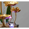 A golden lotus pond tabletop water fountain with purple LED lighting pouring water into petals.