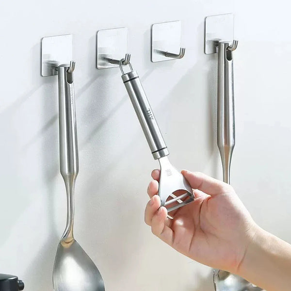 A hand is installing a stainless steel self-adhesive wall hook onto a white surface.