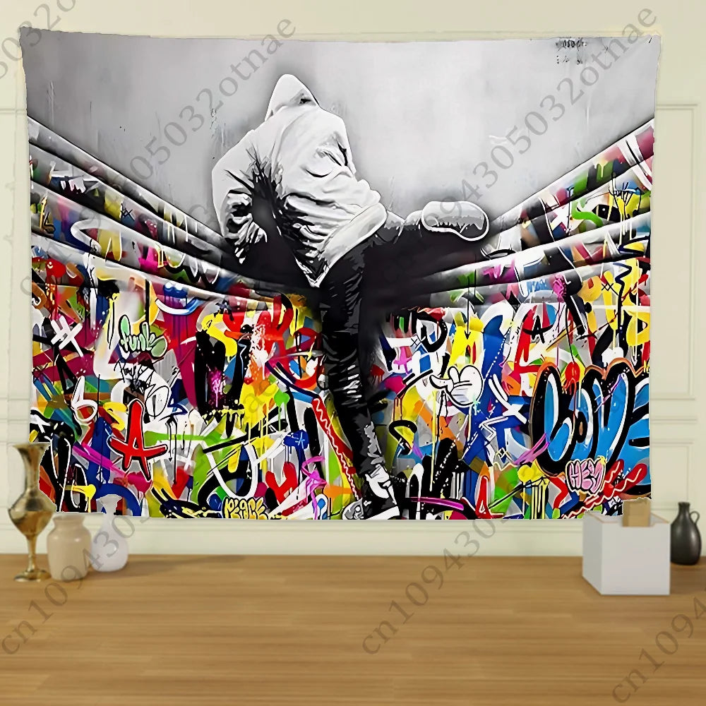 A black and white photograph of a person in a hoodie standing amidst vibrant street graffiti art on a tapestry.