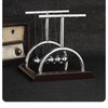 A silver Newton's cradle demonstration featuring balance balls on a dark wooden base.