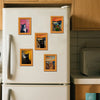 A white refrigerator door decorated with several framed pictures of black cats.
