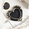 A black vintage baroque resin heart-shaped photo frame with gold accents shown on a white surface.