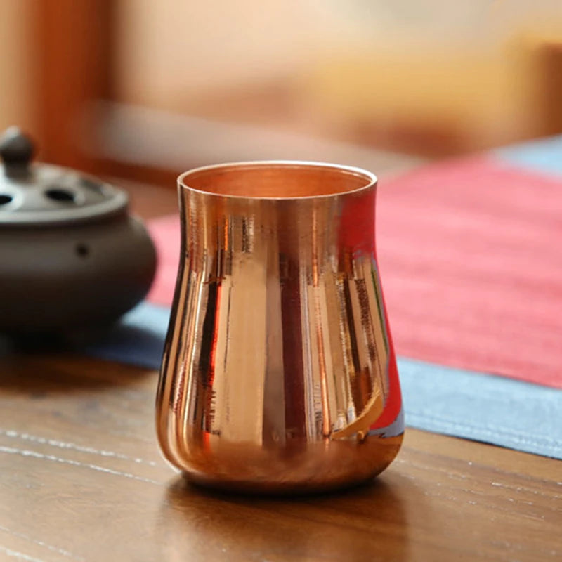 A handcrafted pure copper vintage mug sitting on a wooden surface.