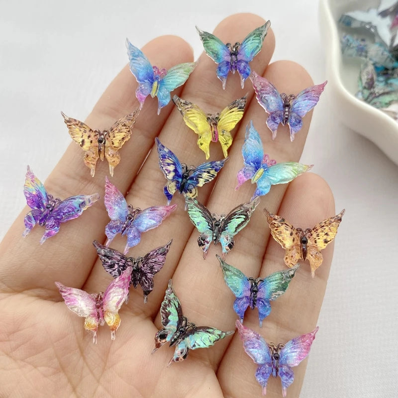 A hand holds a collection of thirty colorful resin butterfly embellishments in various shades of blue, purple, and yellow.